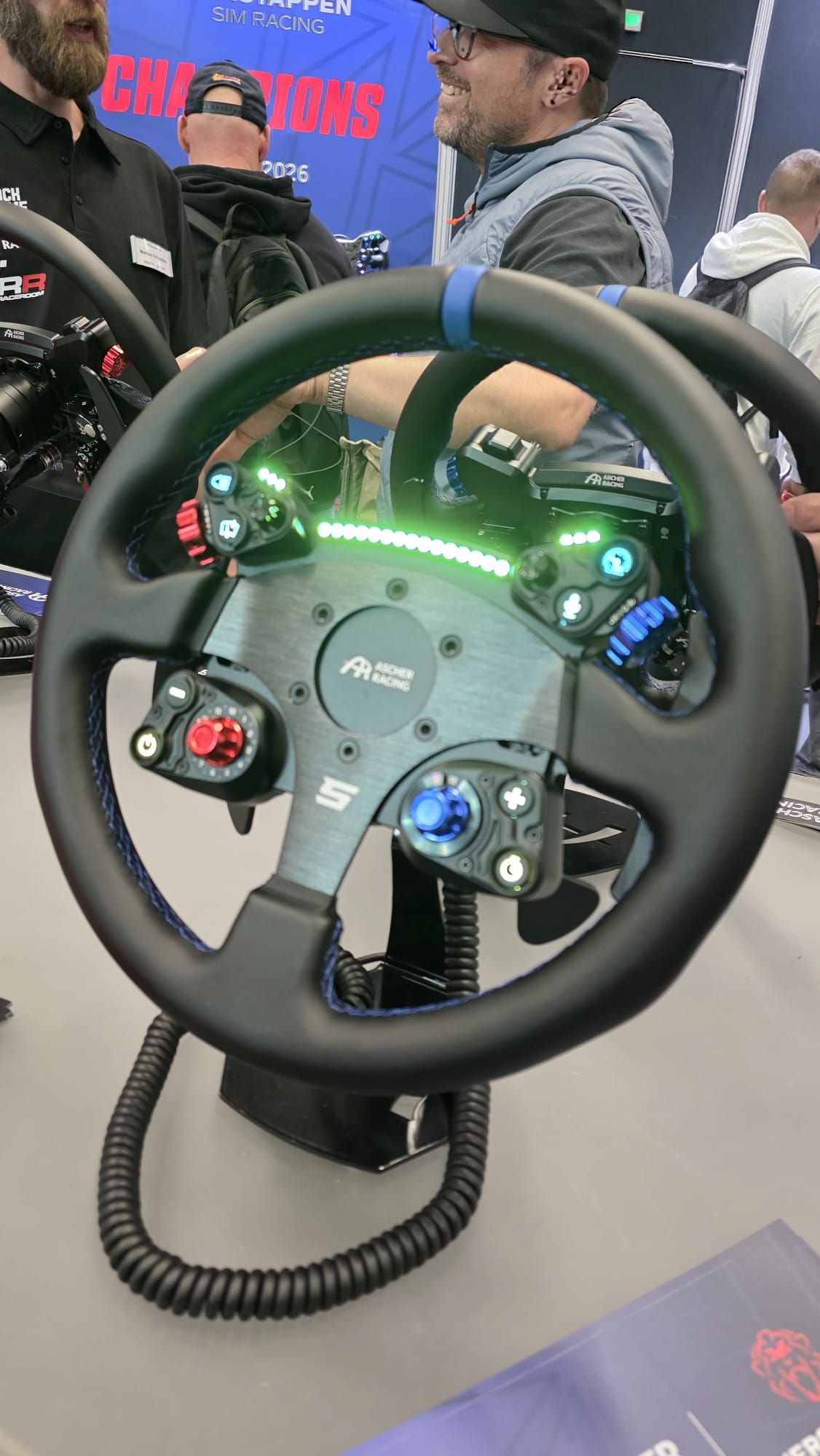 Ascher Racing Aura GT steering wheel and button plate with illuminated controls on display at SimRacing Expo 2026.